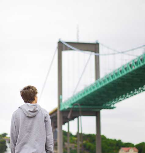 En person som håller en kamera och tittar på en bro.