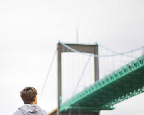 En person som håller en kamera och tittar på en bro.